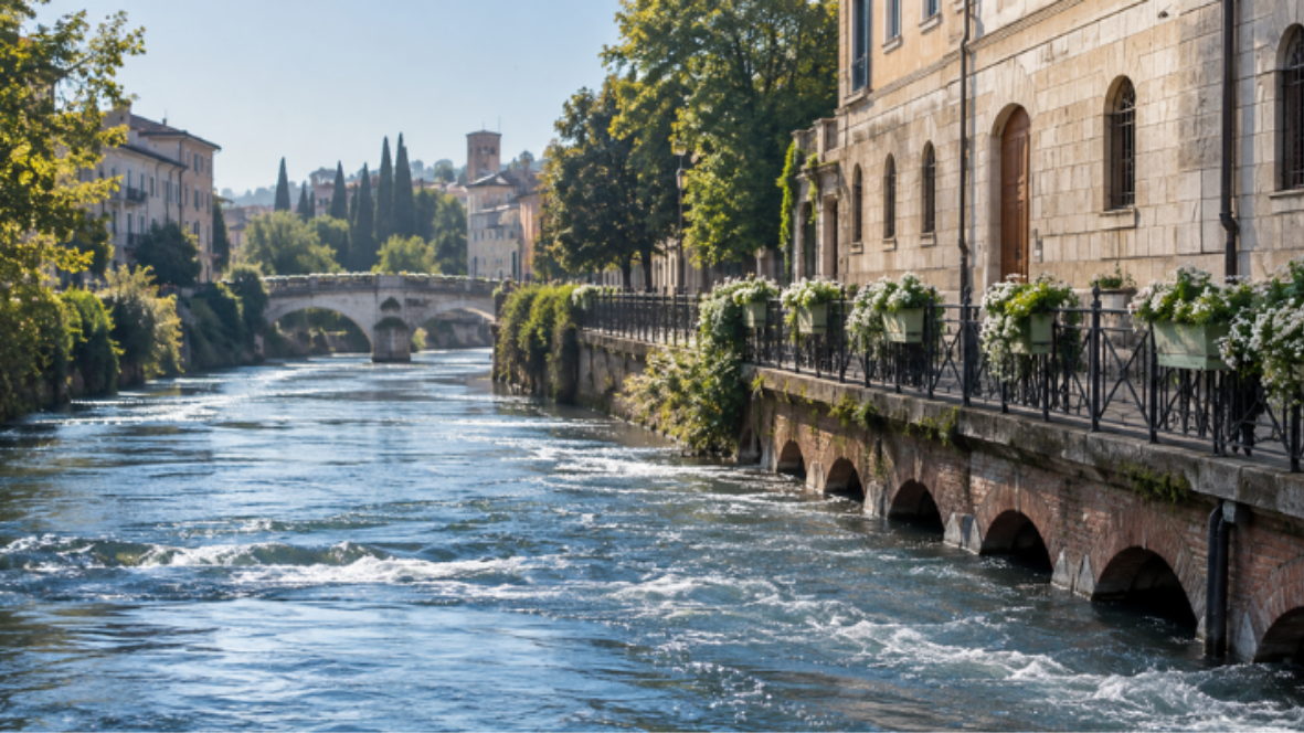 Fiume urbano con ponte ad archi sullo sfondo e sponda in muratura, ambito di applicazione della soluzione Axatel Angel River per il monitoraggio dei corsi d'acqua.