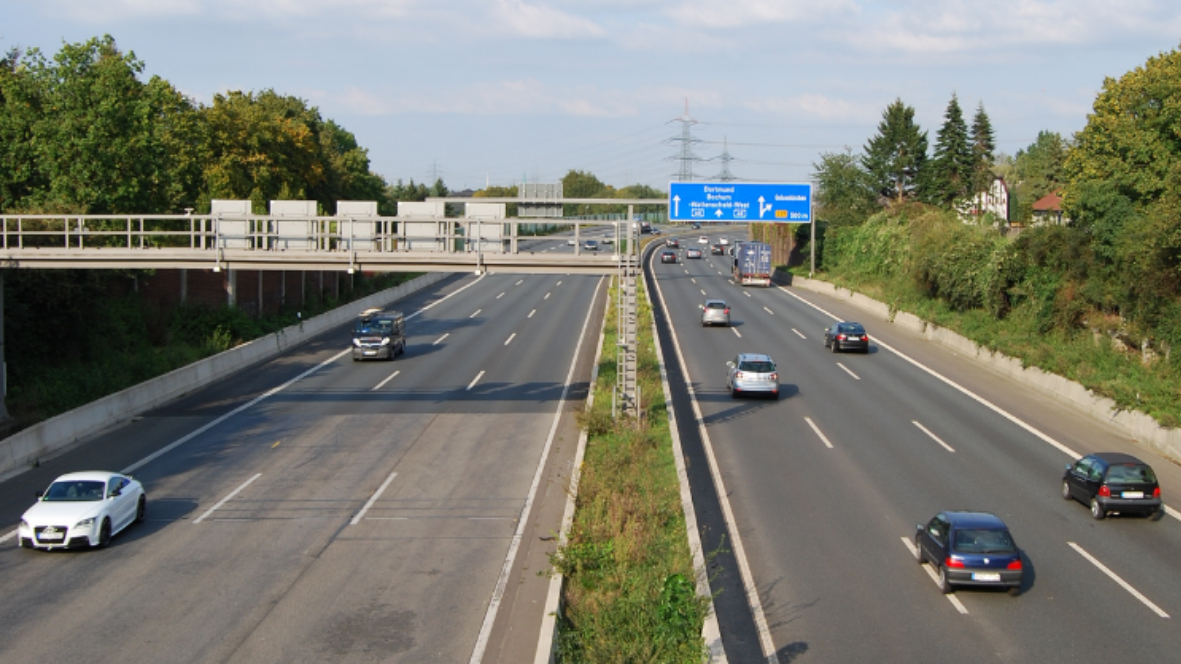 Vista dall'alto di un'arteria autostradale a più corsie con veicoli in transito e portali di segnaletica, contesto d'uso della video analisi Axatel Traffic Alert.